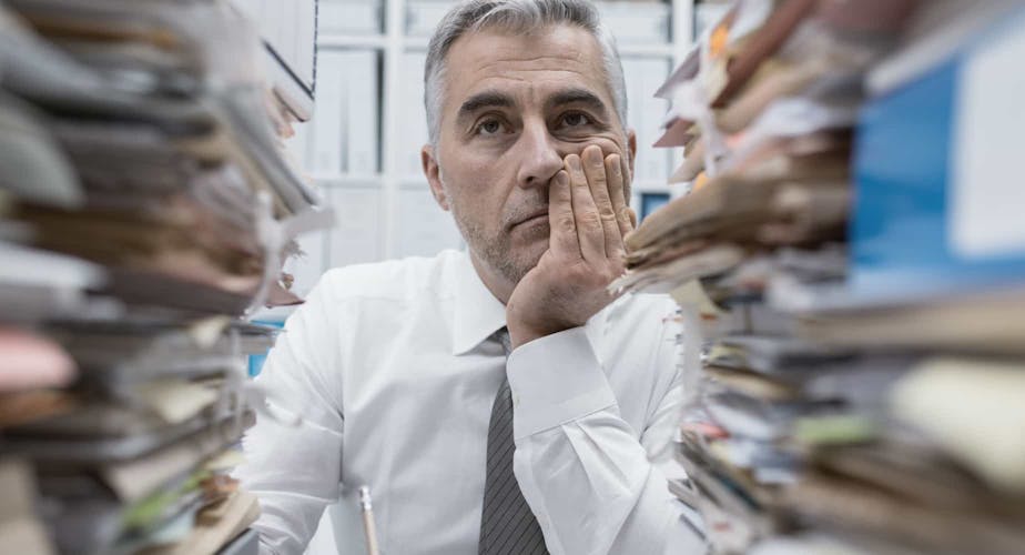 Overwhelmed employee with stacks of paper
